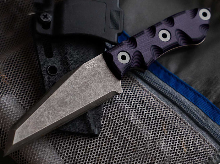 t.kell knife with black handle laying on top of sheath and bag